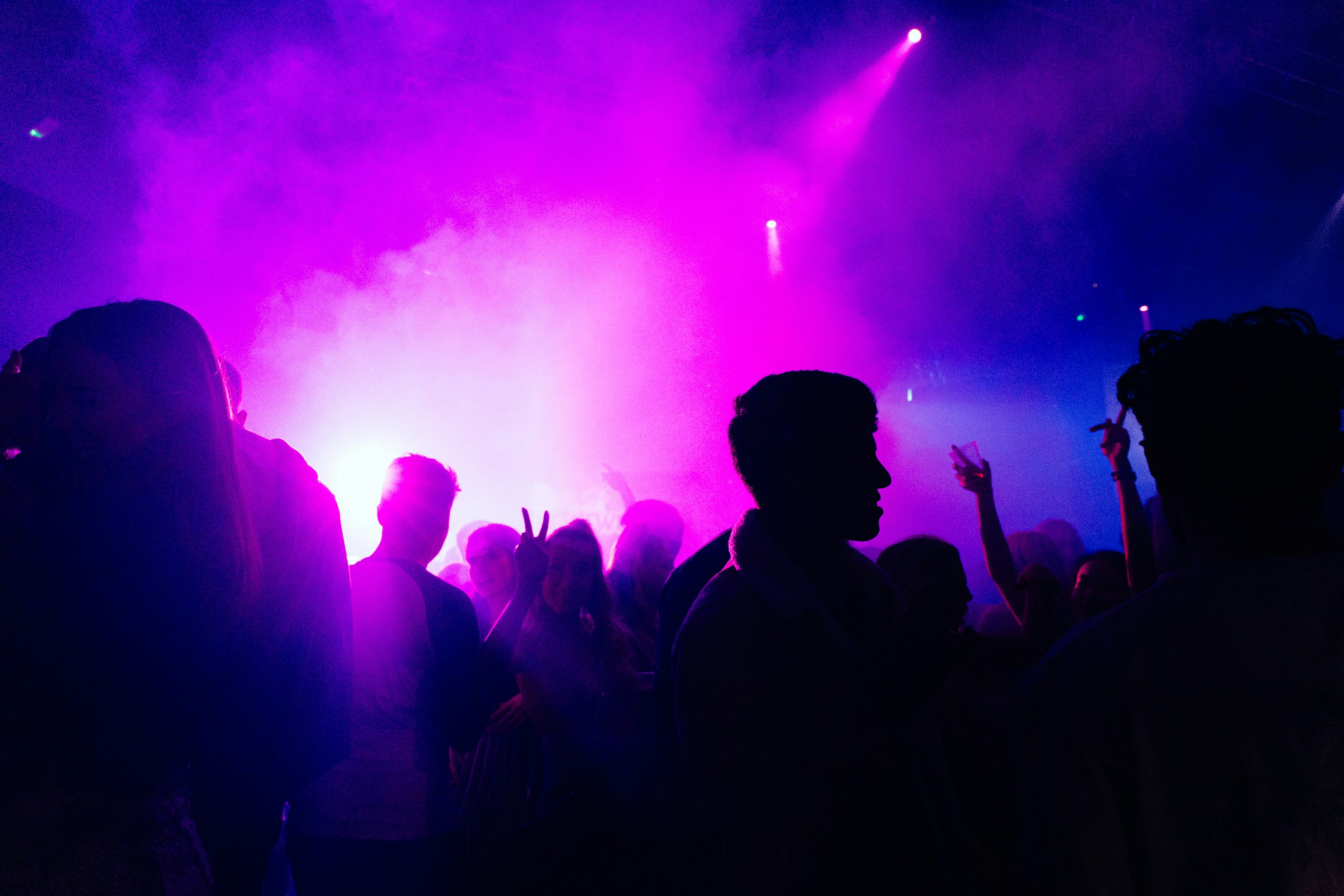 Silhouettes of people in front of club lights